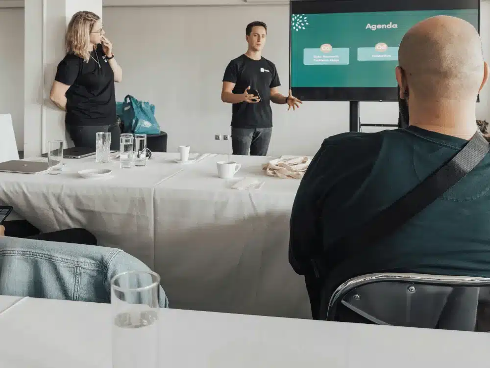 Presenter delivering agenda at team meeting in conference room.