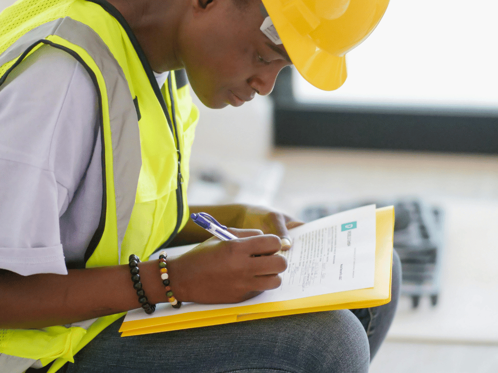 Safety-equipped worker with hard hat engaged in administrative tasks.