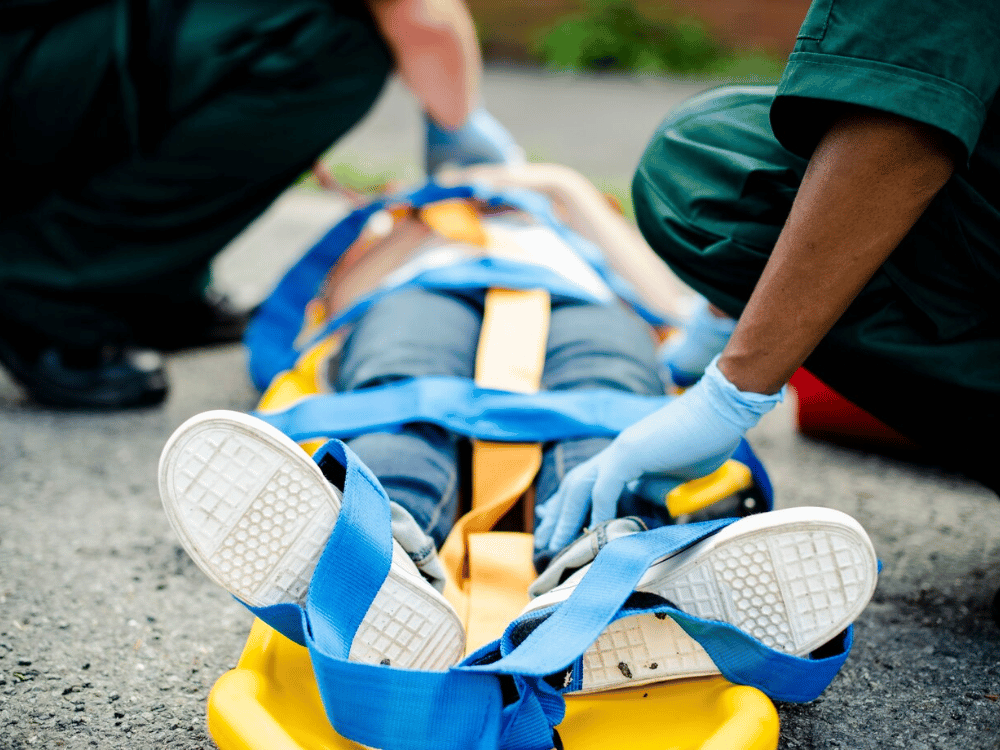 Close-up of emergency responders securing a patient on a stretcher with straps.
