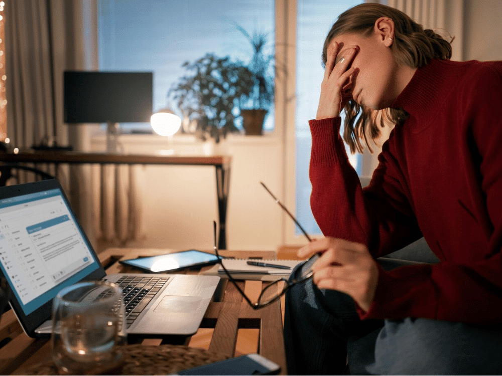 An image of a person holding an eyeglasses while using a laptop.