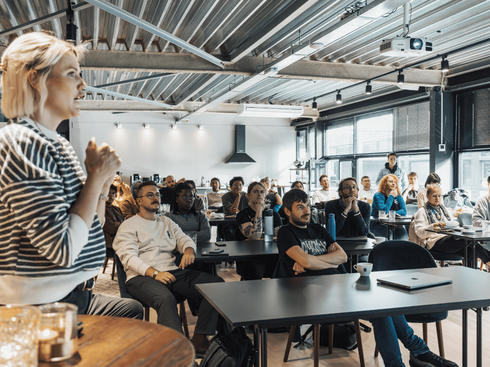 Diverse audience attentively listening to a female presenter at a workshop.