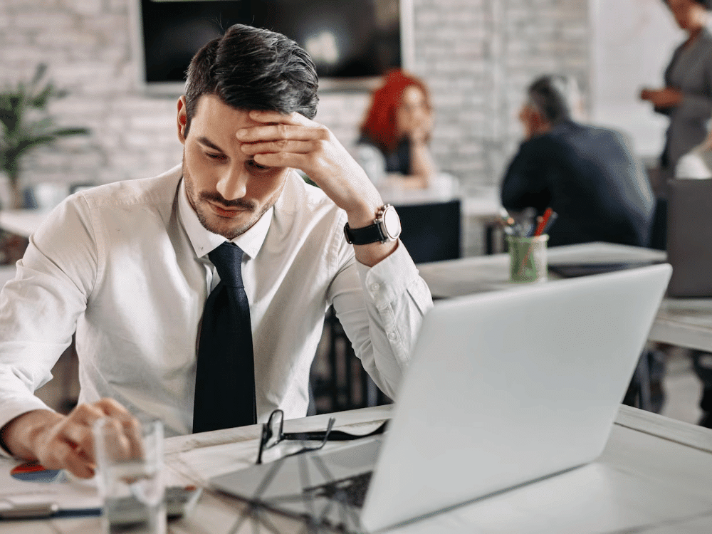 A person in a shirt and tie sitting at a table with laptop.