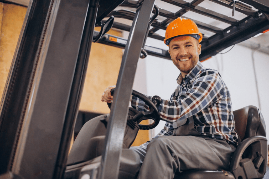 A person sitting on a forklift in a warehouse with a smile.