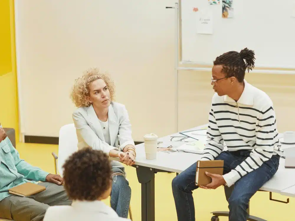 Group discussion in a bright, modern office with a woman and man engaged in conversation.
