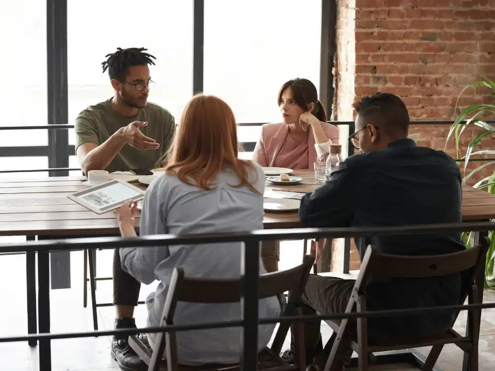 Group discussion at a modern workspace, focusing on a tablet with project details.