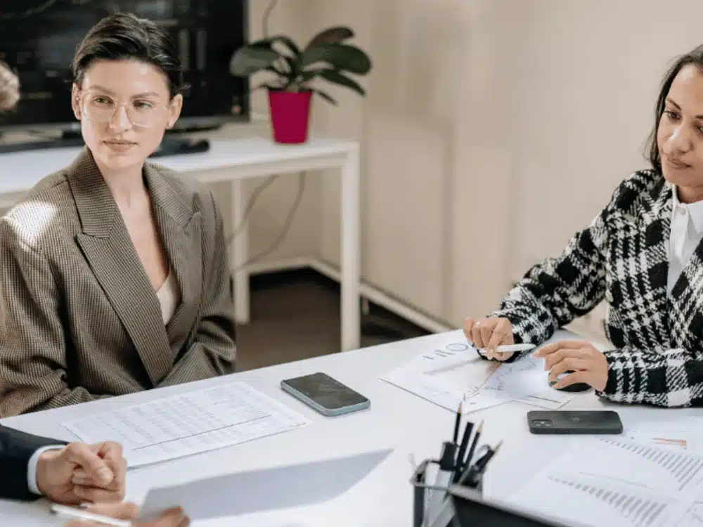 Co-workers in a serious office meeting with charts on table.