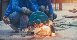 A worker using an abrasive wheel to cut metal
