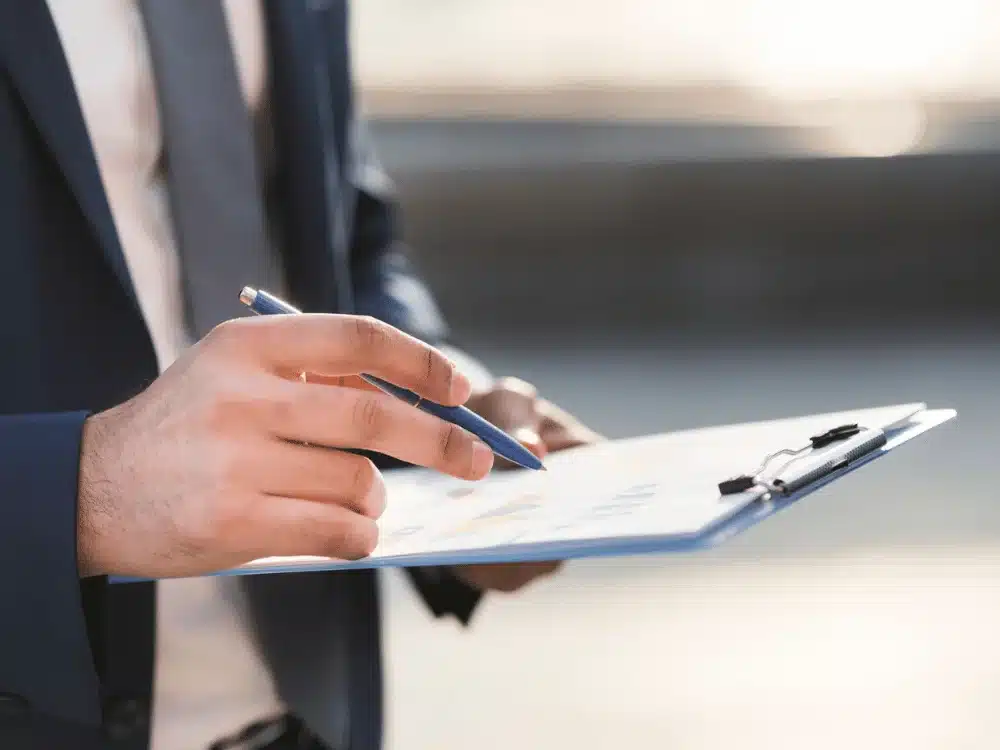 Detailed view of male hands holding a pen and business documents.