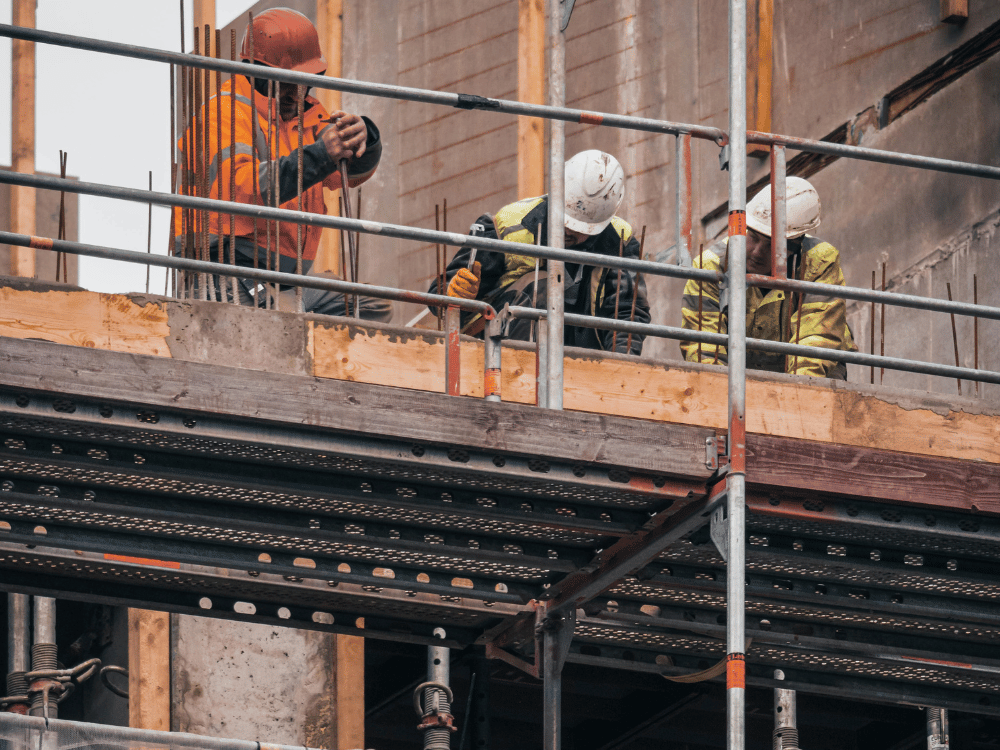 Construction workers on scaffolding inspecting formwork at a site.