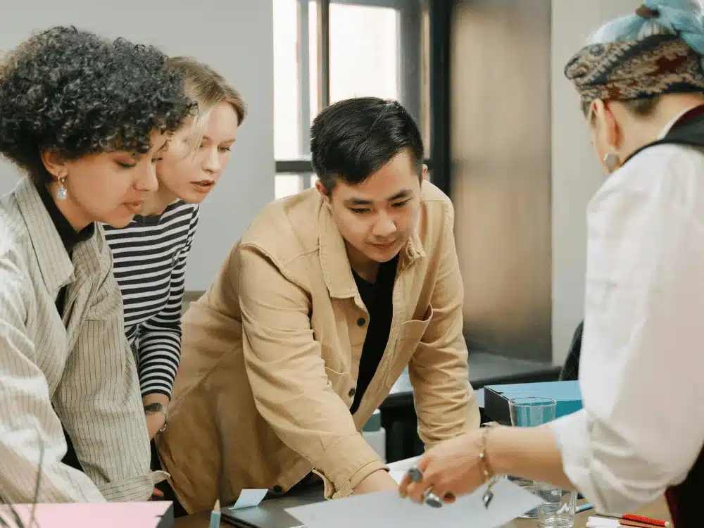 Group of four young adults collaborating around a table, engaged in a discussion.