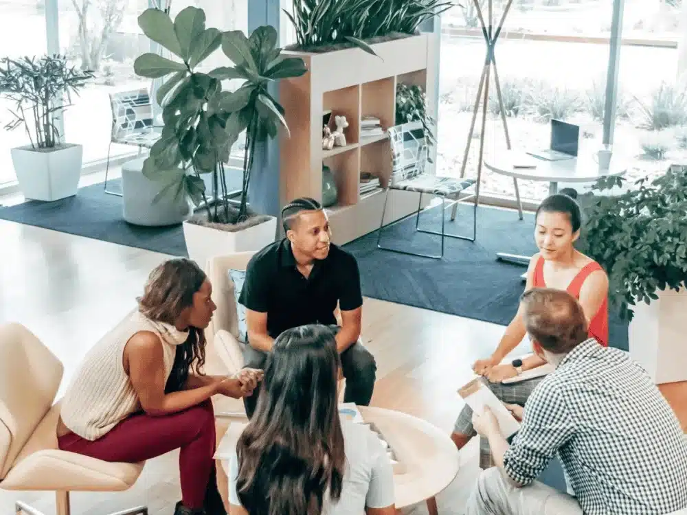 Office workers brainstorming in a relaxed, open-plan office area.