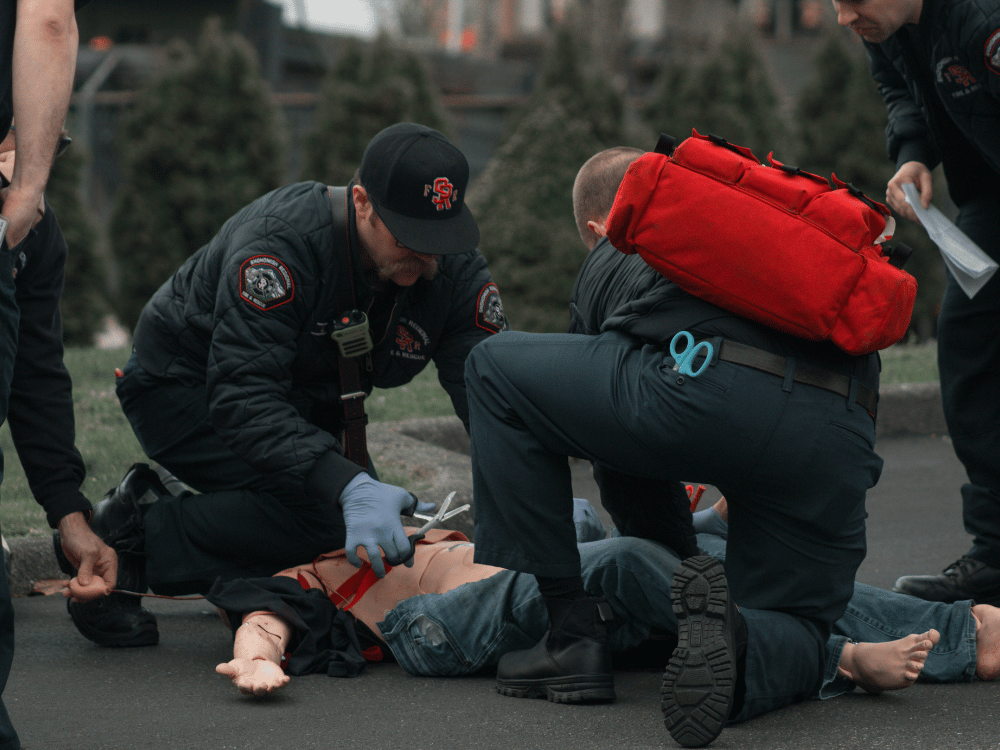 Paramedics performing CPR on a training dummy during an outdoor drill.