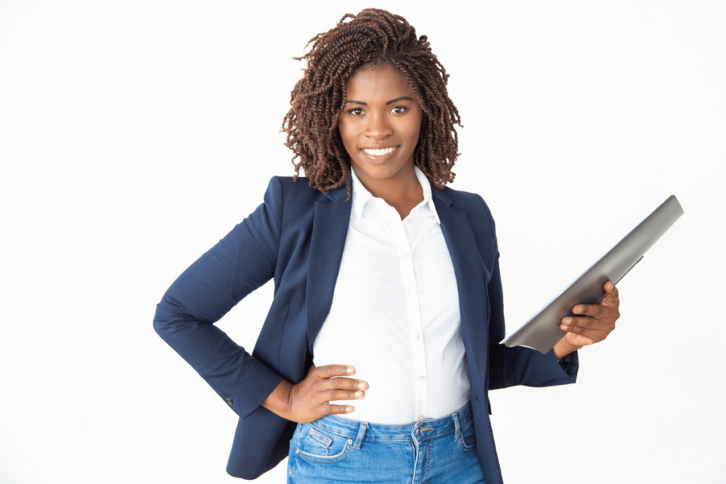 An individual in jeans and a blazer holding a laptop.
