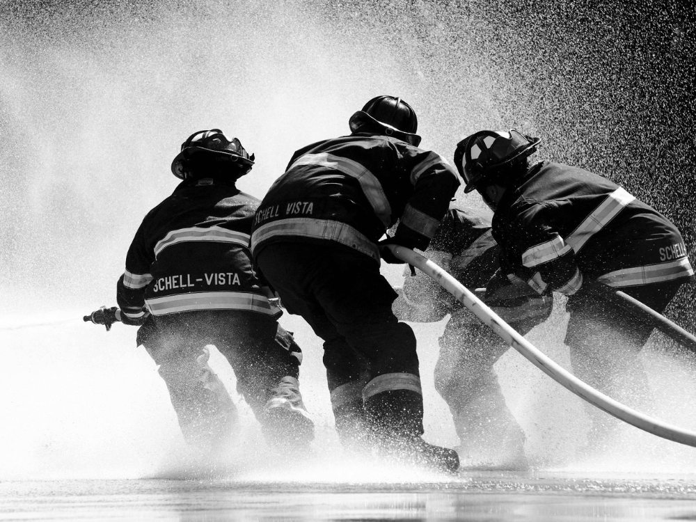 Fire fighters holding a hose of water.