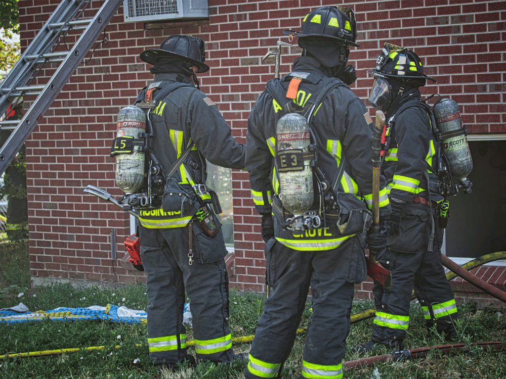 A group of firefighters standing in front of a building.