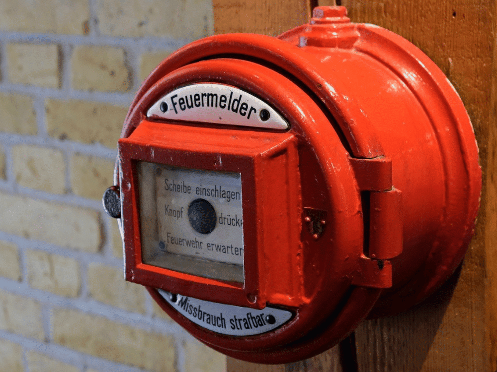 A red fire hydrant on a brick wall.