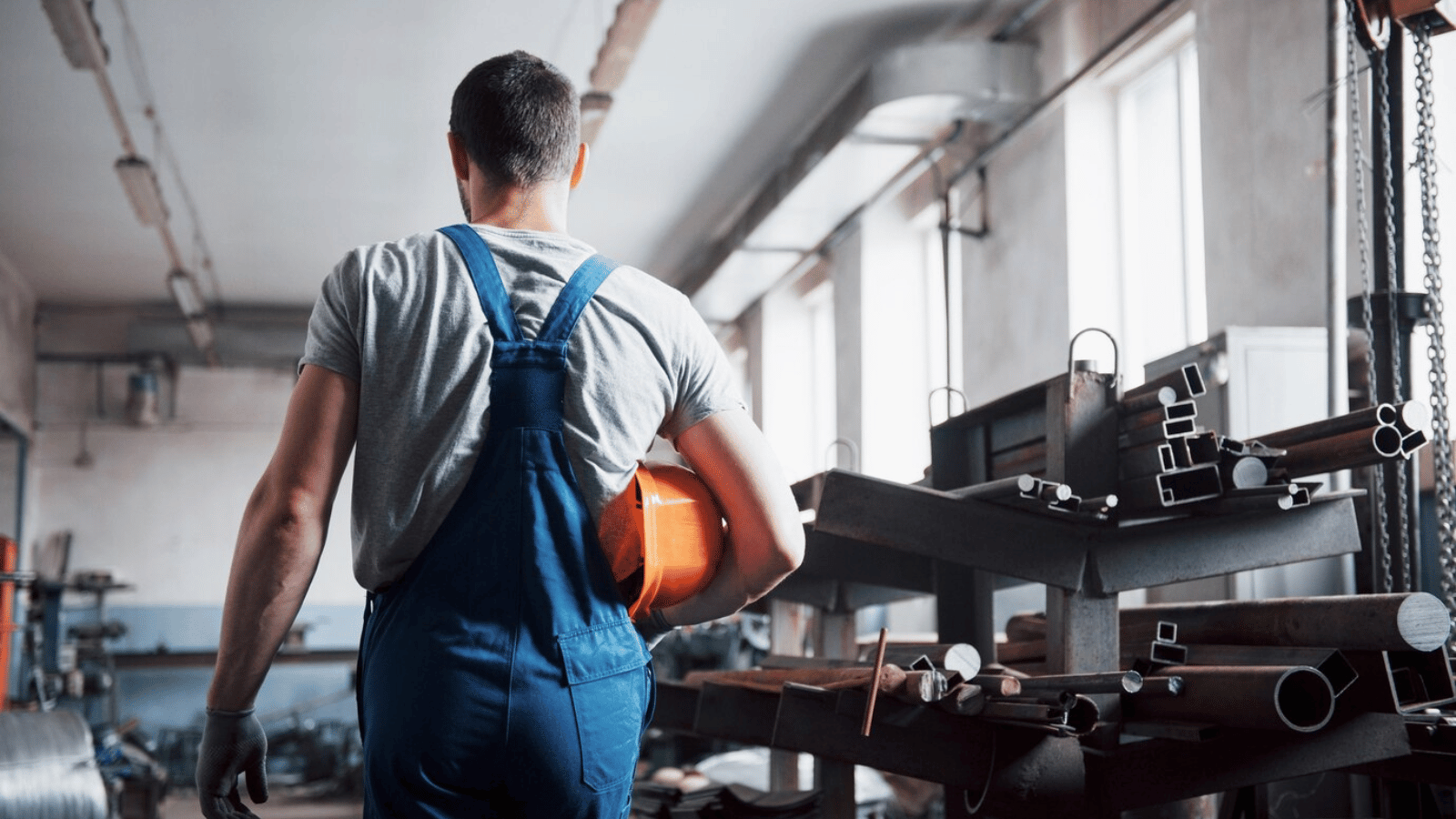 A person in overalls walking through a factory.