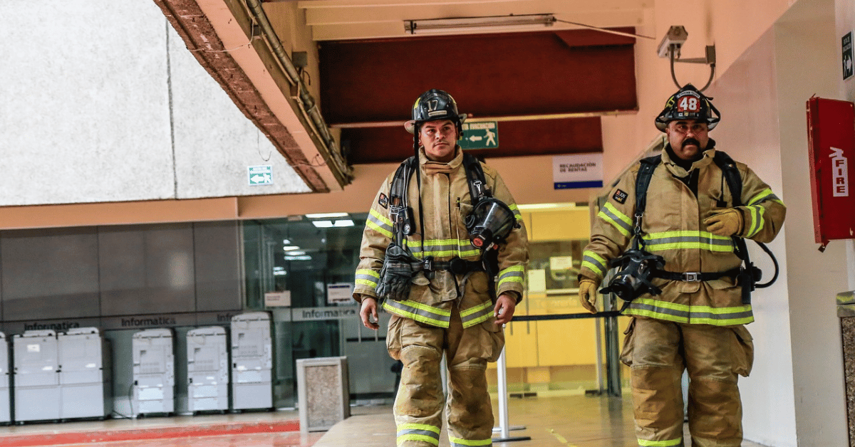 Ready and alert firefighters with helmets in a corridor.