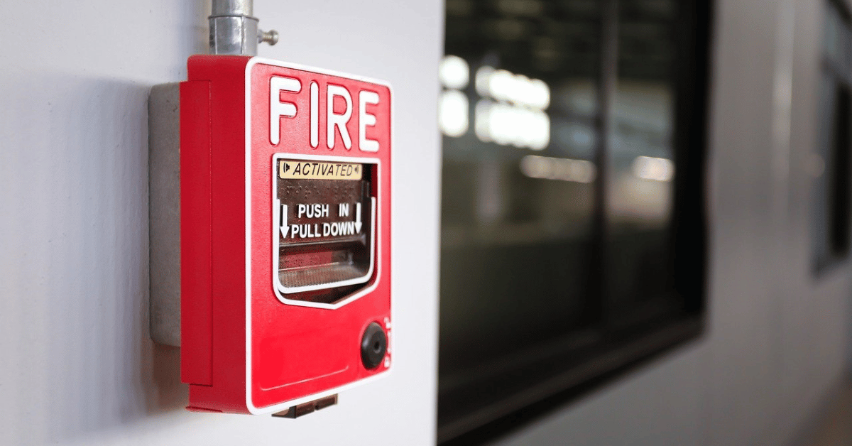 Close-up of a red fire alarm switch on a white wall in an office building