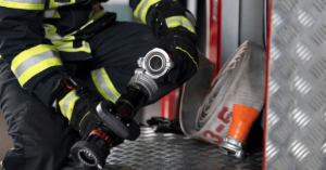 A person in a fireman's uniform is holding a hose.