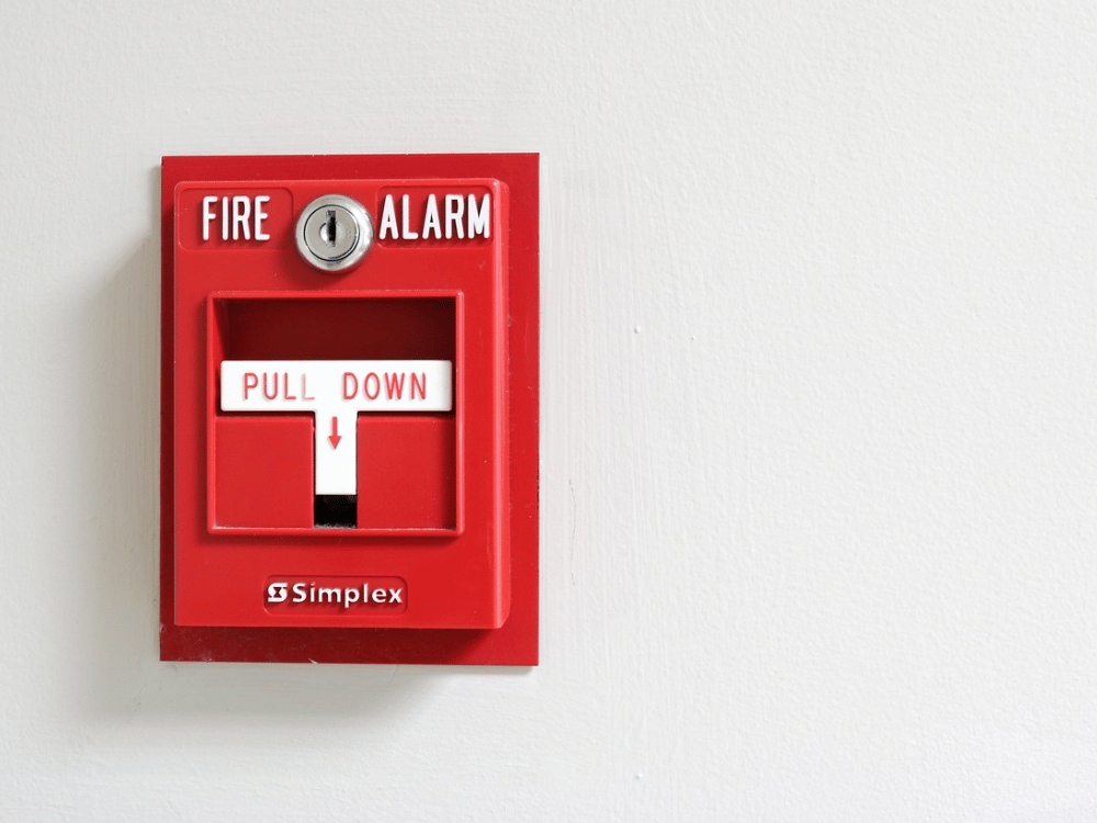 A red fire alarm mounted on a white wall.