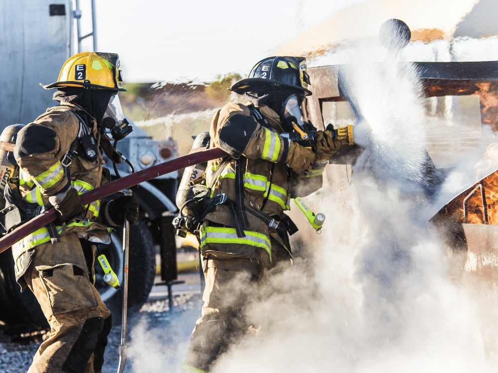 Emergency fire service personnel practicing firefighting techniques on-site.