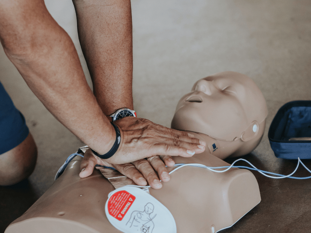 CPR training with a mannequin on the floor.