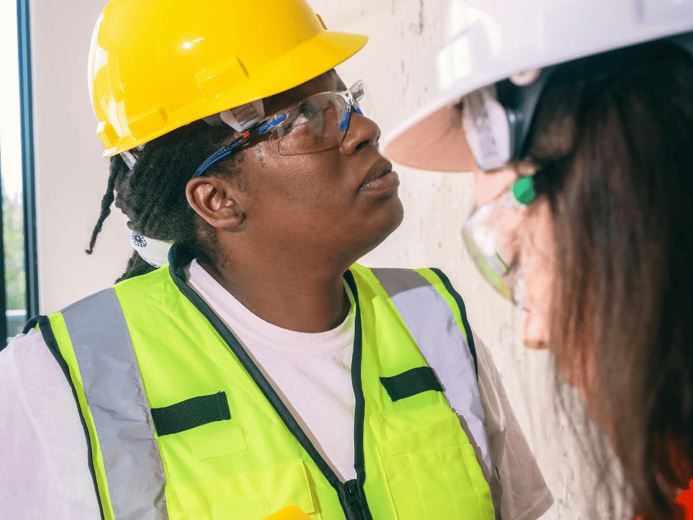 Two women in safety vests engaged in conversation.