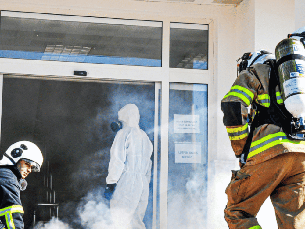 A firefighter extinguishing flames on a building using a powerful water spray to combat the fire.