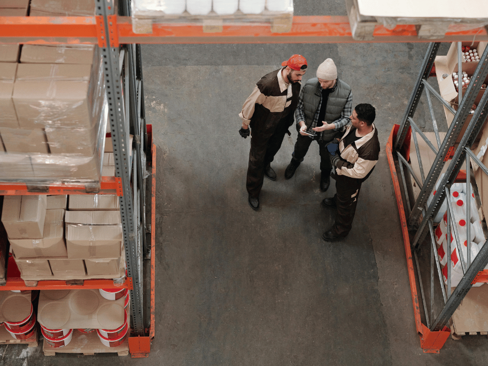 Overhead view of warehouse workers discussing logistics.