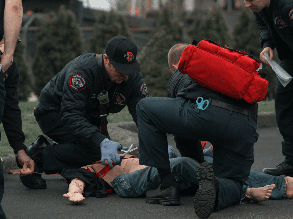 First aid responders practicing life-saving techniques on a mannequin.