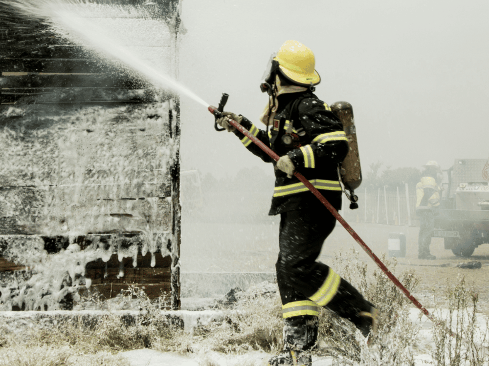 Fire service member in action spraying water on a winter blaze.