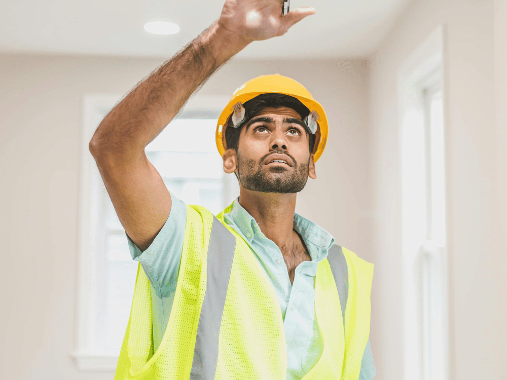 Focused construction inspector in a yellow hard hat examining interior works.