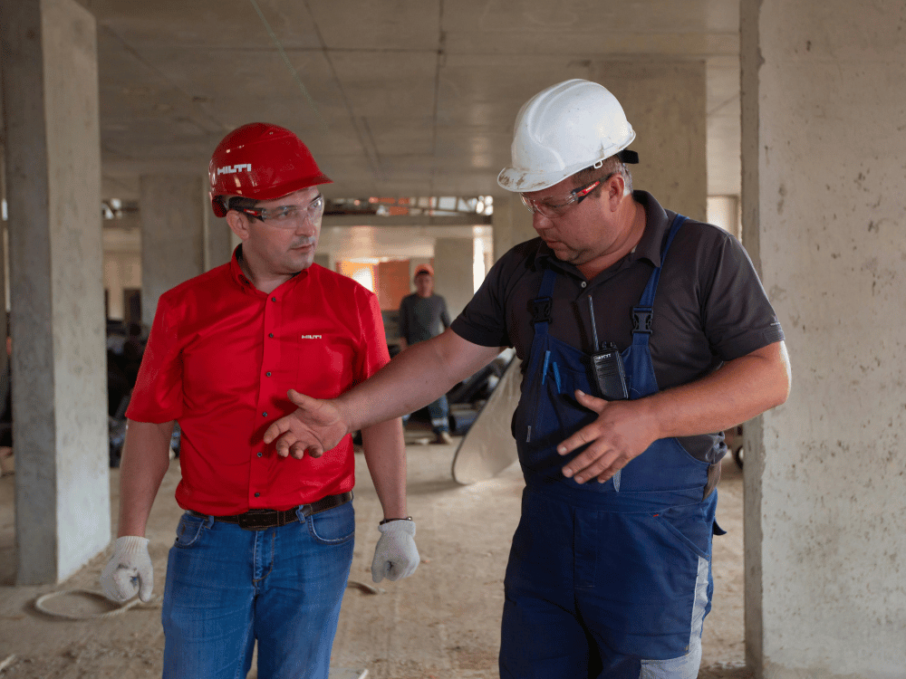 Workers with safety helmets talking about project details in a building.