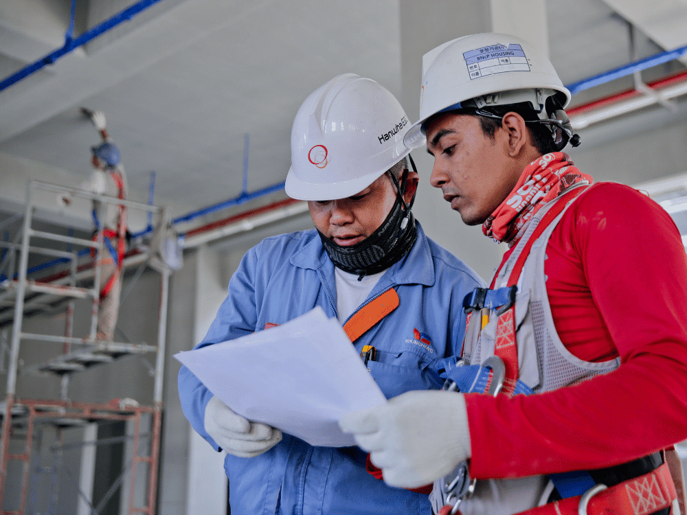 Skilled laborers in protective equipment analyzing building plans.