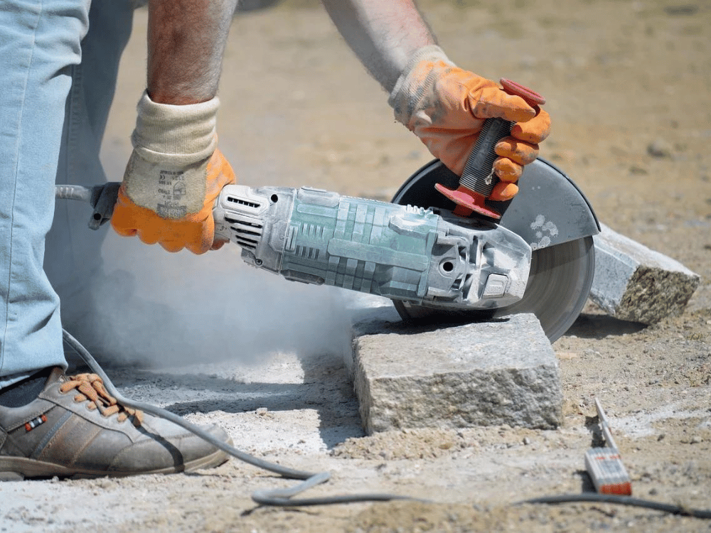 A man operating an electric grinder to cut concrete.