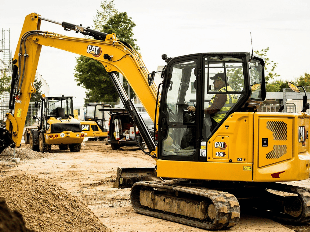 A yellow excavator is parked on a dirt road.