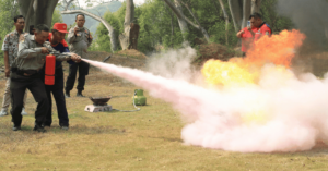 Fire safety training with extinguisher and controlled blaze.
