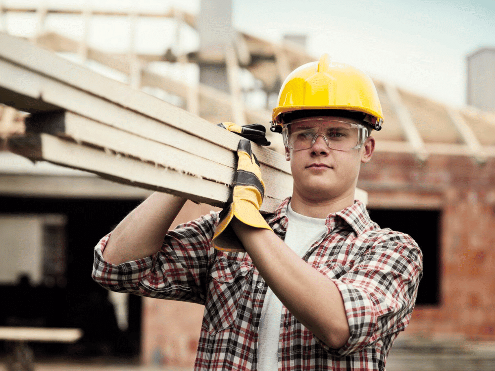 A person in a hard hat holding a piece of wood.