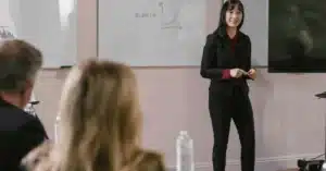 Businesswoman giving a presentation in a conference room with whiteboards.