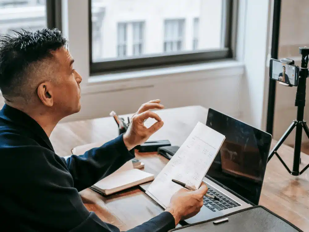 Businessman giving an online presentation, recording with phone camera.
