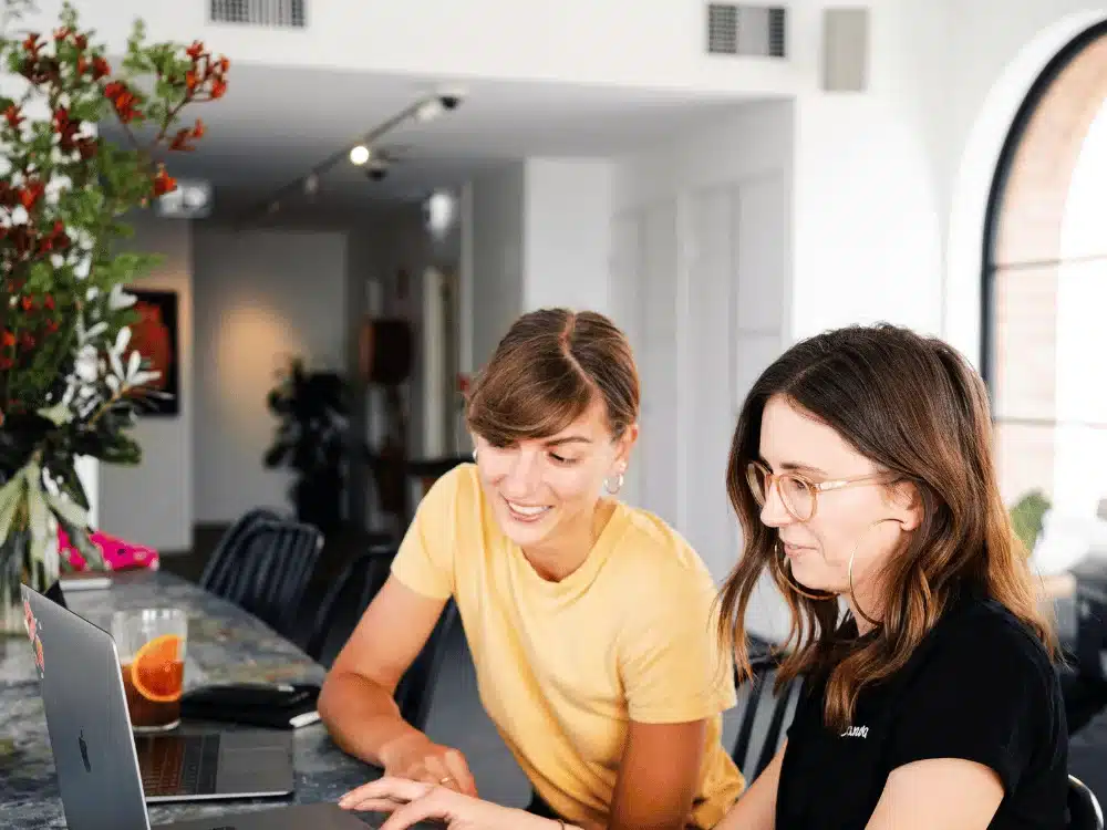 Two women collaborating on a laptop at a stylish workspace.