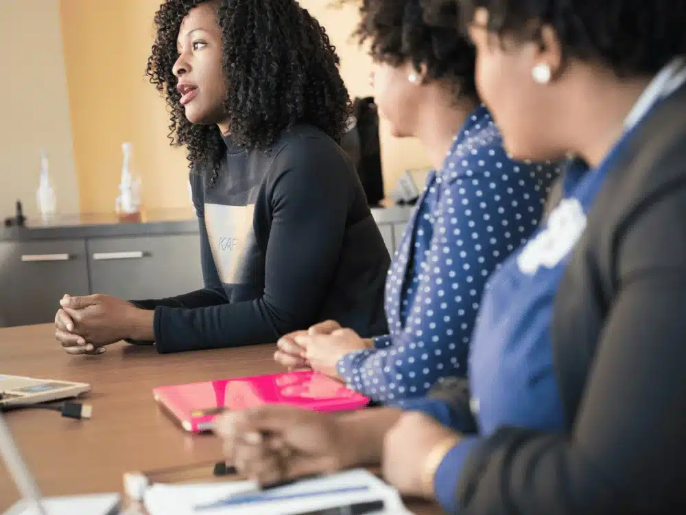 Three professionals engaged in a discussion during a meeting.