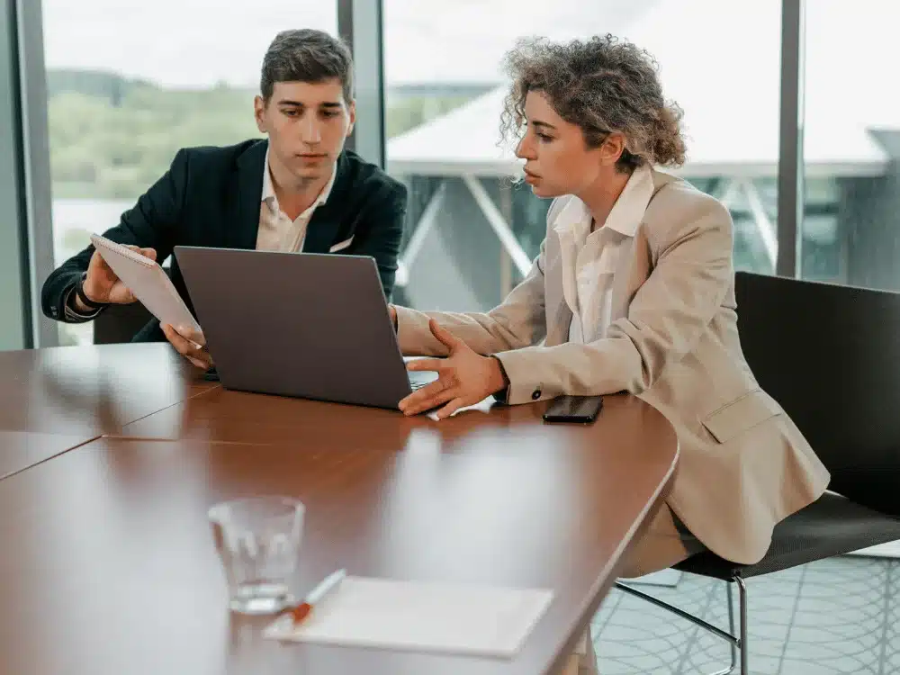 Business partners reviewing documents and a laptop during a discussion.