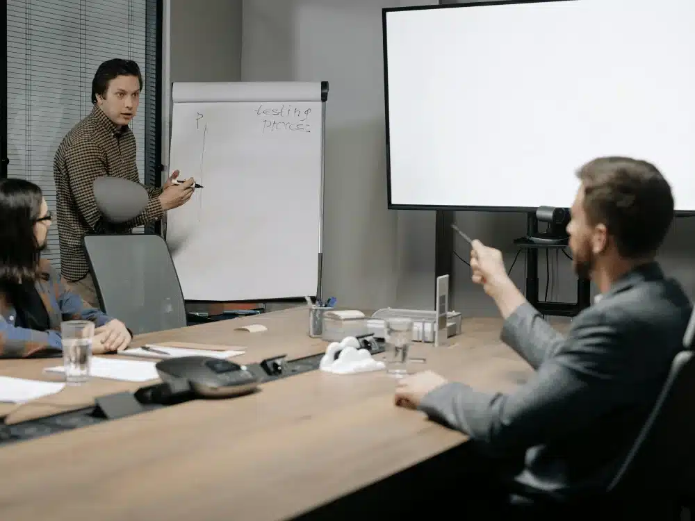 Team meeting with a presentation on a flip chart and discussions around a conference table.