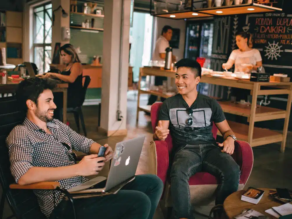 Two friends chatting and laughing in a cozy coffee shop.