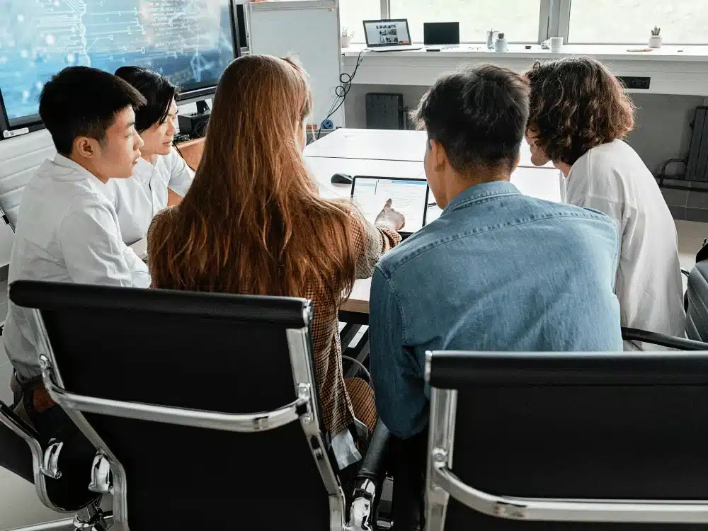 Team collaborating on a project, seated around a conference table with laptops.